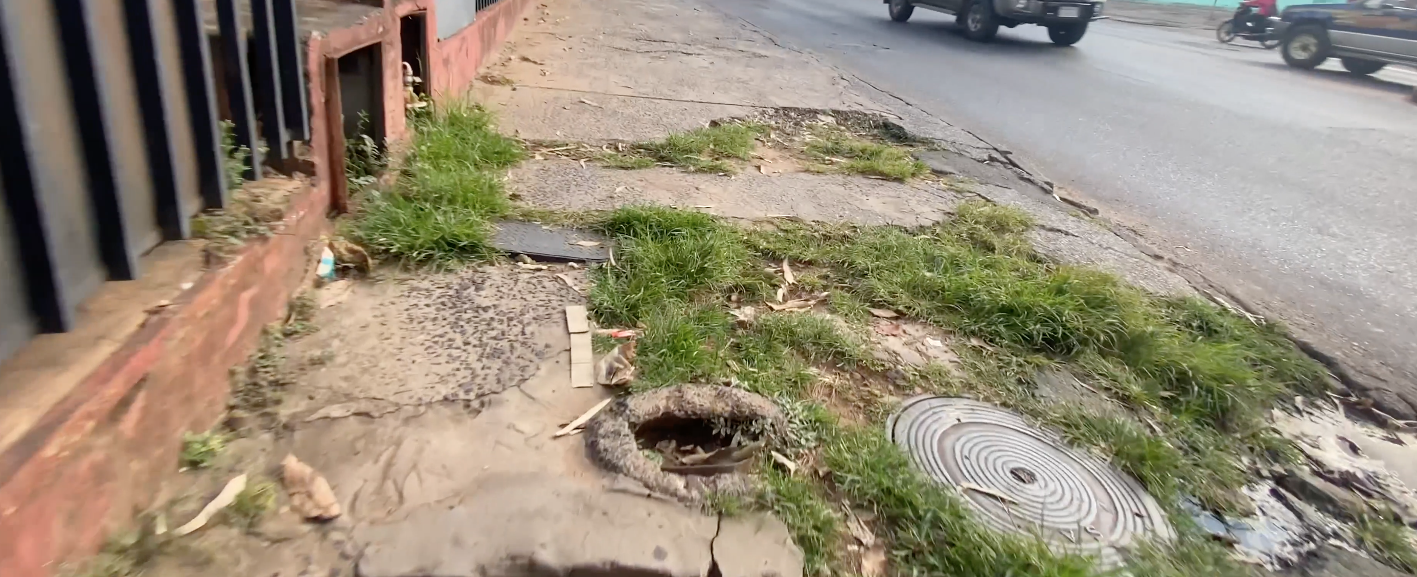 Precarious sidewalk with holes and grass in Paraguay