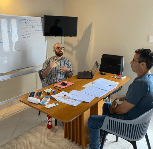 Raúl teaching a Spanish class with his student with lots of papers on the table